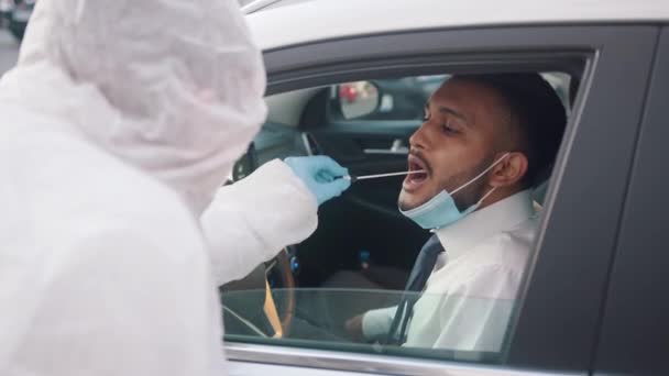 Conduire à travers la station d'essai covid. Docteur effectuant un test d'écouvillonnage sur le conducteur — Video