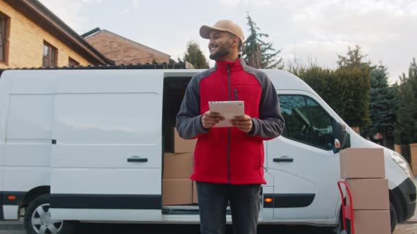 Genç adam paket hakkında bilgi edinmek için tablet kullanıyor. Paketi teslim ediyorum. — Stok video