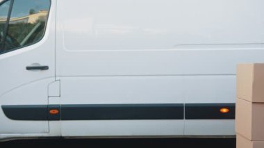 Yüz maskeli bir adam troleybüste karton kutuları itiyor. Covid19 salgını sırasında paket teslimatı