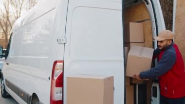 Teslimatçılar sokakta karton kutuları boşaltıyor.