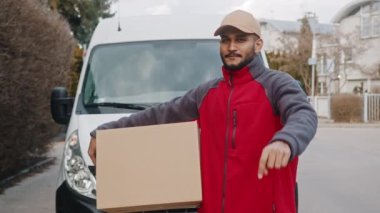Paket teslimatçısı kamerayı işaret edip paketi veriyor.