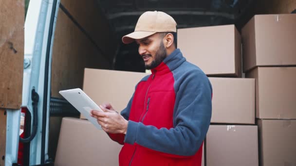 Νέοι courier χρησιμοποιώντας tablet μπροστά από το φορτηγό γεμάτο με κουτιά από χαρτόνι. Παράδοση του pardel — Αρχείο Βίντεο