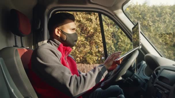 Giovane uomo indiano con maschera viso di stoffa utilizzando il computer portatile nel furgone — Video Stock