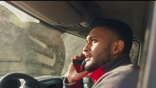 Hombre indio sentado en la camioneta y conversando por teléfono — Vídeos de Stock