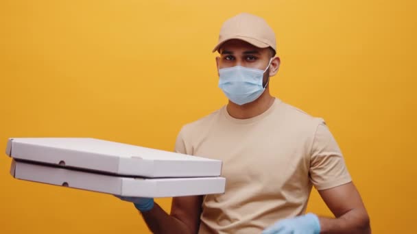 Jonge pizzabezorger met gezichtsmasker en handschoenen met pizzadozen en met ok teken — Stockvideo