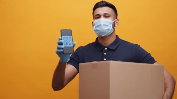 Entrega homem com máscara facial segurando pacote e mostrando código QR no smartphone — Vídeo de Stock