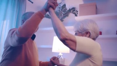 Otel odasında disko ışıklarıyla dans eden mutlu yaşlı çift. Sevgililer Günü ya da yıldönümü kutlaması