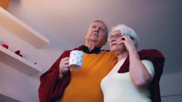 上了年纪的夫妻一边看电视一边拥抱和打电话. — 图库视频影像