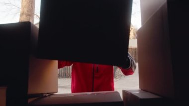 Genç adam kamyondan karton kutuları çıkarıyor.