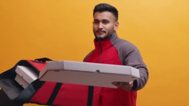 Bir elinde yemek torbası olan Hintli bir adam müşteriye pizza veriyor.