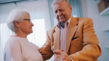 Resmi kıyafetle evde dans eden mutlu yaşlı çift. Yaşlılıkta aşk ve flört.