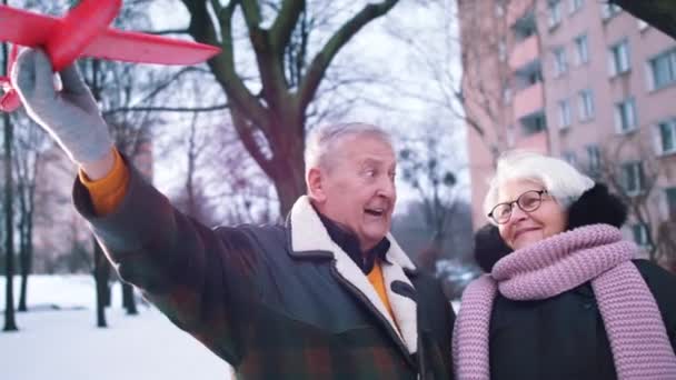 Elderly couple planing winter holidays. Man flying toy airplane — Stock Video