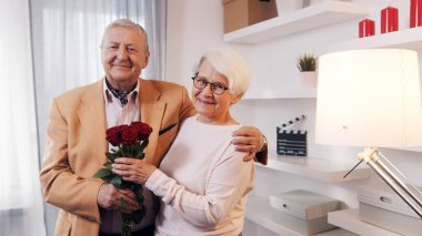 Sevgililer günü ve yaşlılıkla flört. Yaşlı çift yıldönümünü kutluyor. Adam karısına kırmızı güller veriyor.