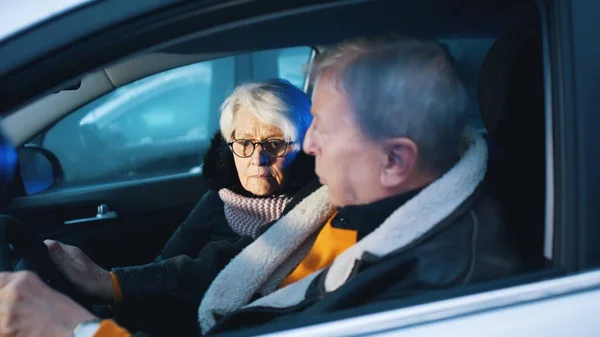 Elderly couple in the car confused with flashing police lights. Speeding ticket. Man and woman having argument in the car
