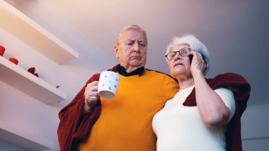 Yaşlı bir çift televizyon izlerken sarılıyor ve telefonda konuşuyor.. 