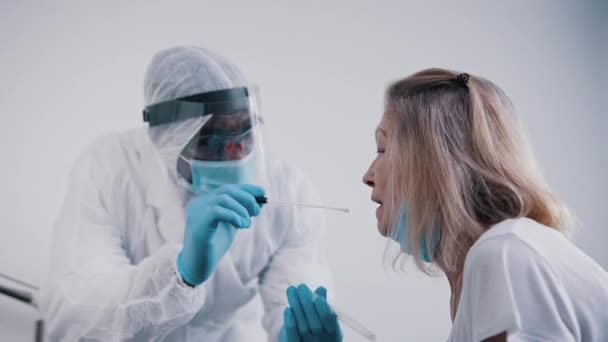 Médico realizando una prueba covid de hisopo nasal en una mujer mayor — Vídeo de stock