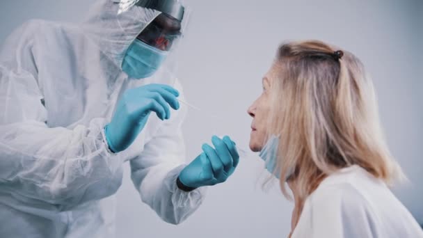 У пожилой женщины тест covid19. Африканский американский врач берет образец из ее носа — стоковое видео