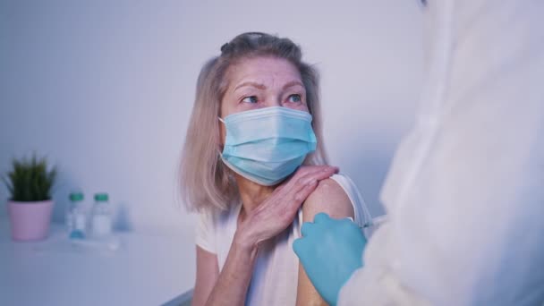 身着防护服的护士在一位老年妇女的胳膊上注射防止鱼子酱的疫苗 — 图库视频影像