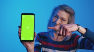 Akıllı telefondaki yeşil ekranı gösteren yaşlı kadın.