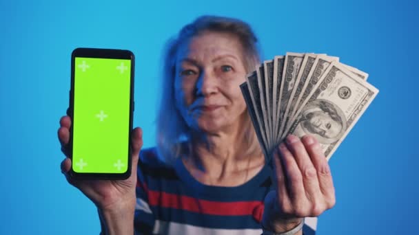 Stará žena drží smartphone se zelenou obrazovkou a dolarovými bankovkami. Investiční aplikace — Stock video