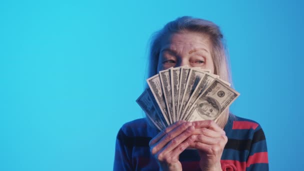 Mujer mayor sosteniendo ventilador de dinero en frente de su cara — Vídeo de stock