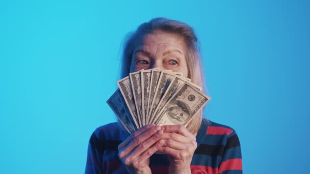 Rico anciana sosteniendo el dinero ventilador en frente de su cara y mirando a su alrededor — Vídeo de stock