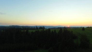 Çam ormanları ve yeşil tepeler üzerinde görkemli günbatımı, Zakopane dağı