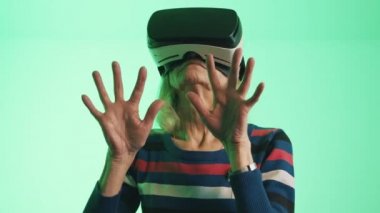 Havaya dokunan VR kulaklıklı yaşlı beyaz kadın.