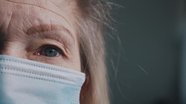 Μάτι ηλικιωμένης γυναίκας με ρυτιδιασμένο δέρμα κάτω από ιατρική μάσκα. Πολύ κοντά. — Αρχείο Βίντεο