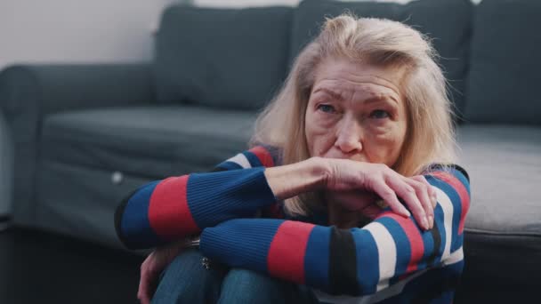 Femme âgée pensive ayant mal à la tête. Vieille dame solitaire assise sur le sol dans le salon — Video