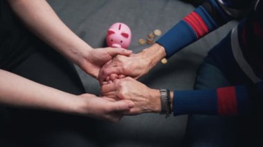 Yaklaş, genç adam yaşlı bir kadının kırışık elini kırık domuz kumbarasının üzerinde tut.