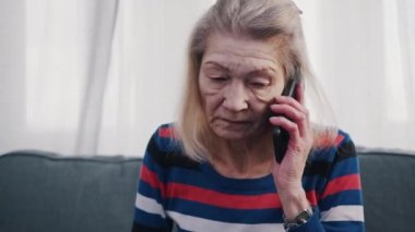 Telefon etmek için akıllı telefon kullanan yaşlı bir kadın. Kötü haberler alıyorum.