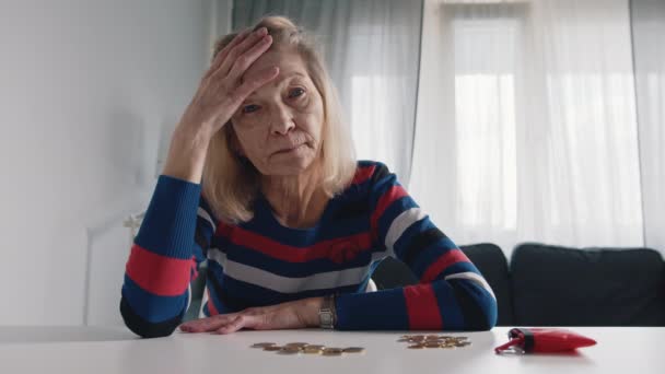 Besorgte alte Frau, der das Geld ausgeht. Münzen zählen auf dem Tisch — Stockvideo