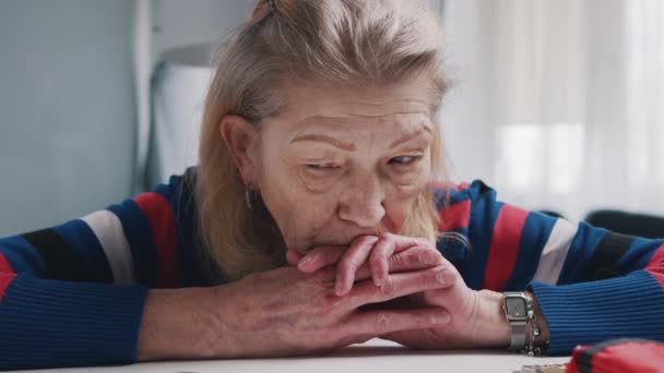 Отчаянная пенсионерка смотрит на небольшое количество монет на столе — стоковое видео