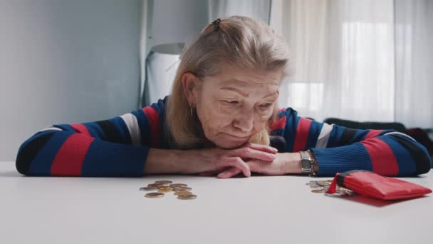 Відчайдушна стара жінка пенсіонерка дивиться на невелику кількість монет на столі. Низька пенсія — стокове відео