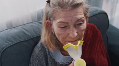 Yaşlı kadın evinde astım spreyi kullanıyor.