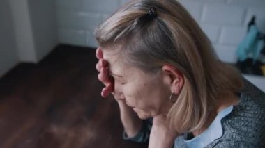 Çaresiz, yalnız, yaşlı kadın baş ağrısı çekiyor.