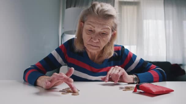 Бедная старуха считает монеты на столе. Низкая пенсия и недостаток средств — стоковое видео