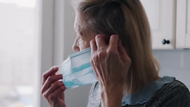 Oudere eenzame vrouw zet medische masker over haar gezicht — Stockvideo