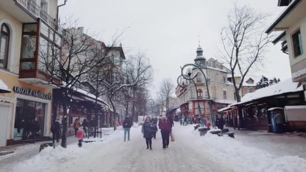 Polonya 'nın Zakopane kentindeki Krupowki caddesinde kar altında yürüyen insanlar. — Stok video