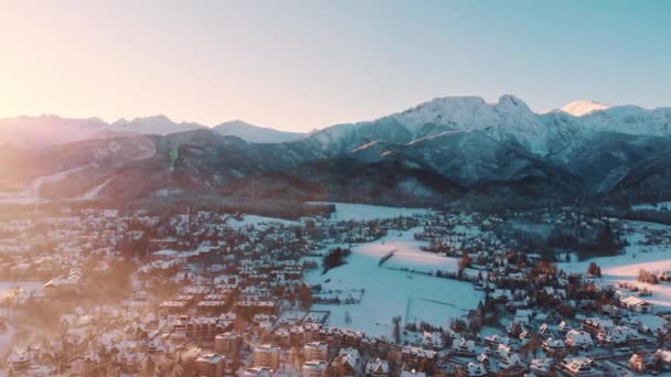 Cidade coberta de neve com montanhas no fundo contra o céu claro - Panorâmica — Vídeo de Stock