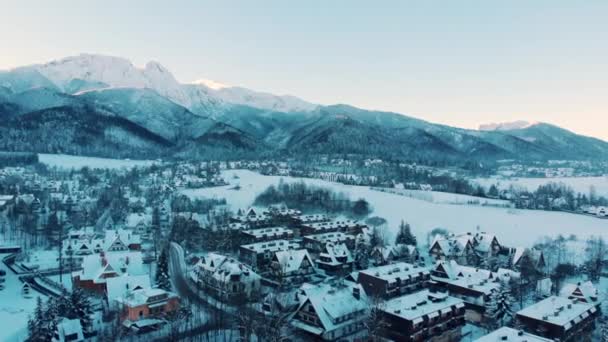 Luftlandschaft. Schneebedeckte Berge in einer Stadt mit schneebedeckten Häusern und Bäumen — Stockvideo