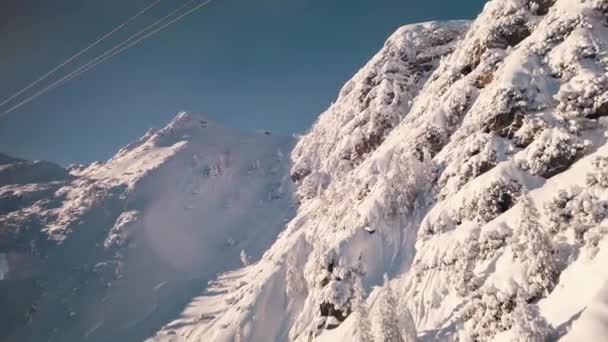 Panoramiczny zapis dwóch kolejki linowej na torze narciarskim ze śnieżnymi górami — Wideo stockowe
