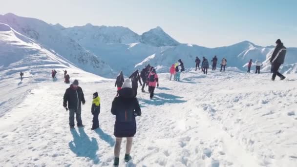 A turisták és a gyerekek a hóval borított gerincen. Hólapátos hegyek Tiszta égbolt — Stock videók