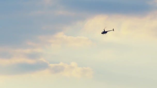 Helicóptero volando alto contra el cielo azul con nubes blancas en la mañana — Vídeo de stock