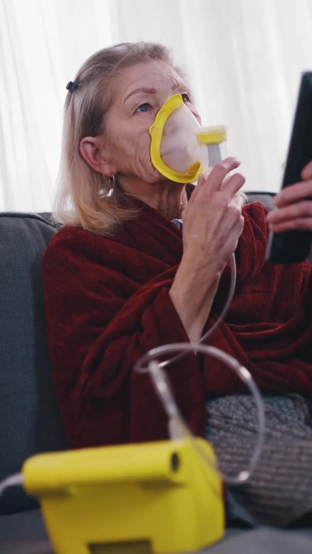 Vertical. Mujer mayor usando inhalador mientras ve la televisión — Vídeos de Stock