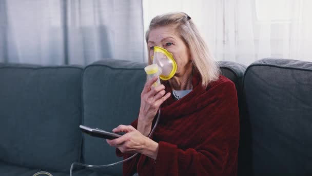 Senior kaukasische Frau mit Inhalator während Fernsehen — Stockvideo