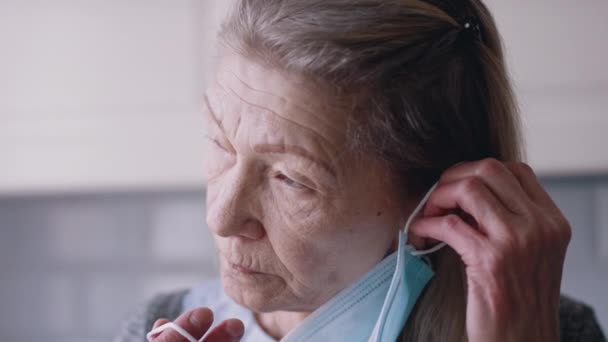 Portrét staré ženy, jak si doma nasazuje masku — Stock video