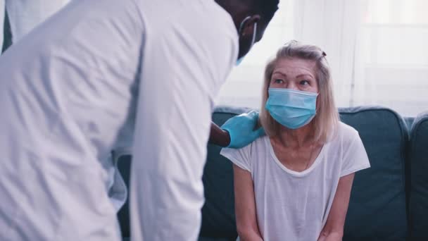 Arzt klopft einer älteren Frau mit Gesichtsmaske auf die Schulter — Stockvideo