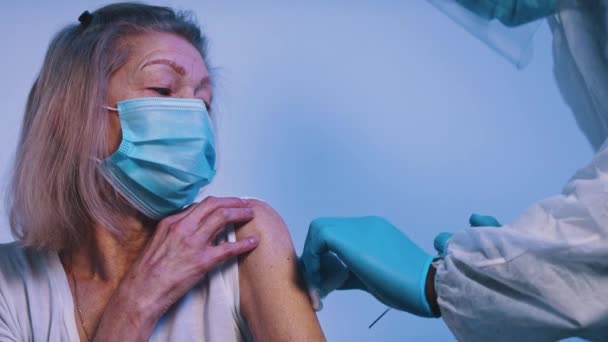 Доктор дает вакцину Ковиду пожилой женщине в маске для лица — стоковое видео